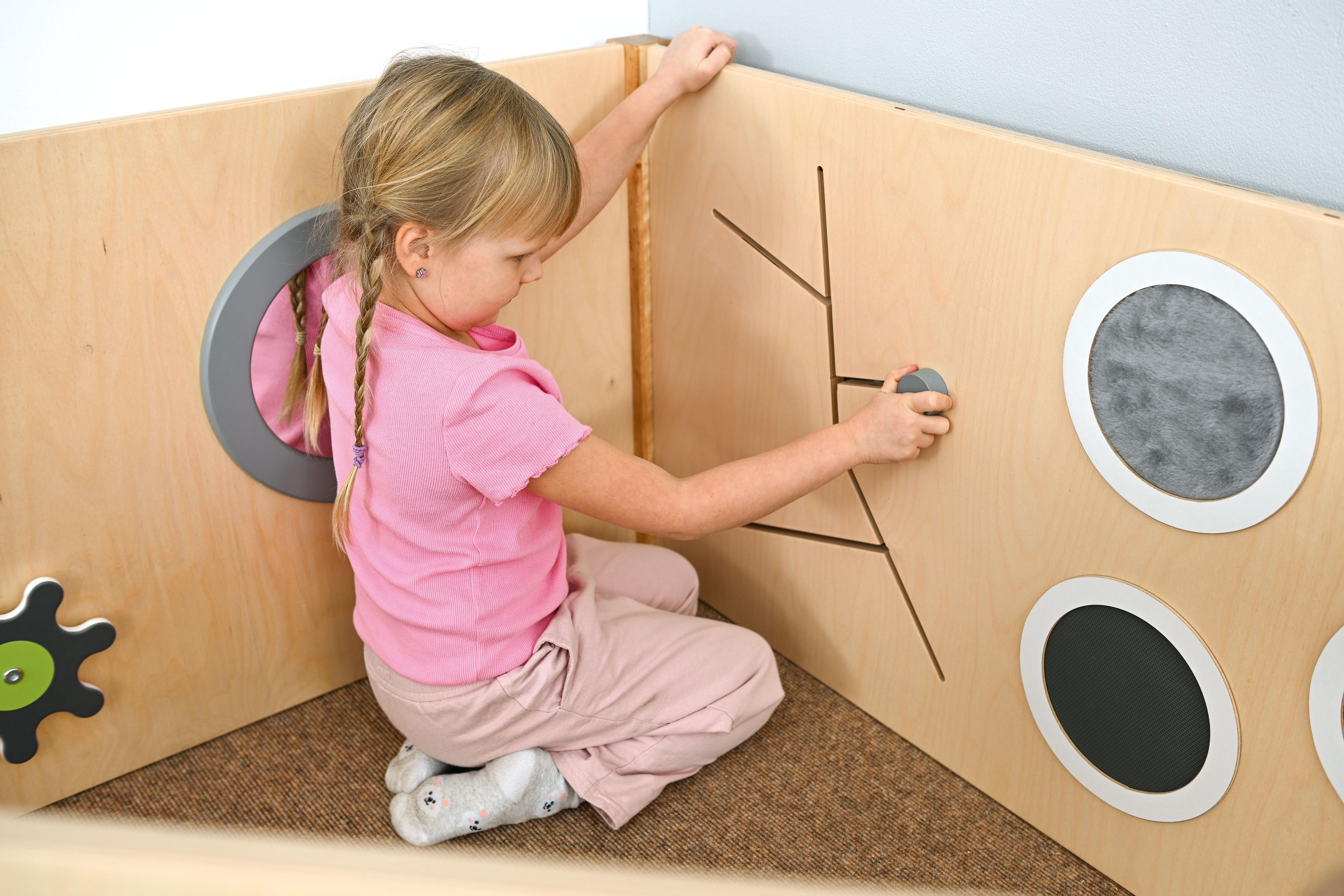 Sensorische Spielecke mit Hochebene, Kind spielt, Naturtöne.