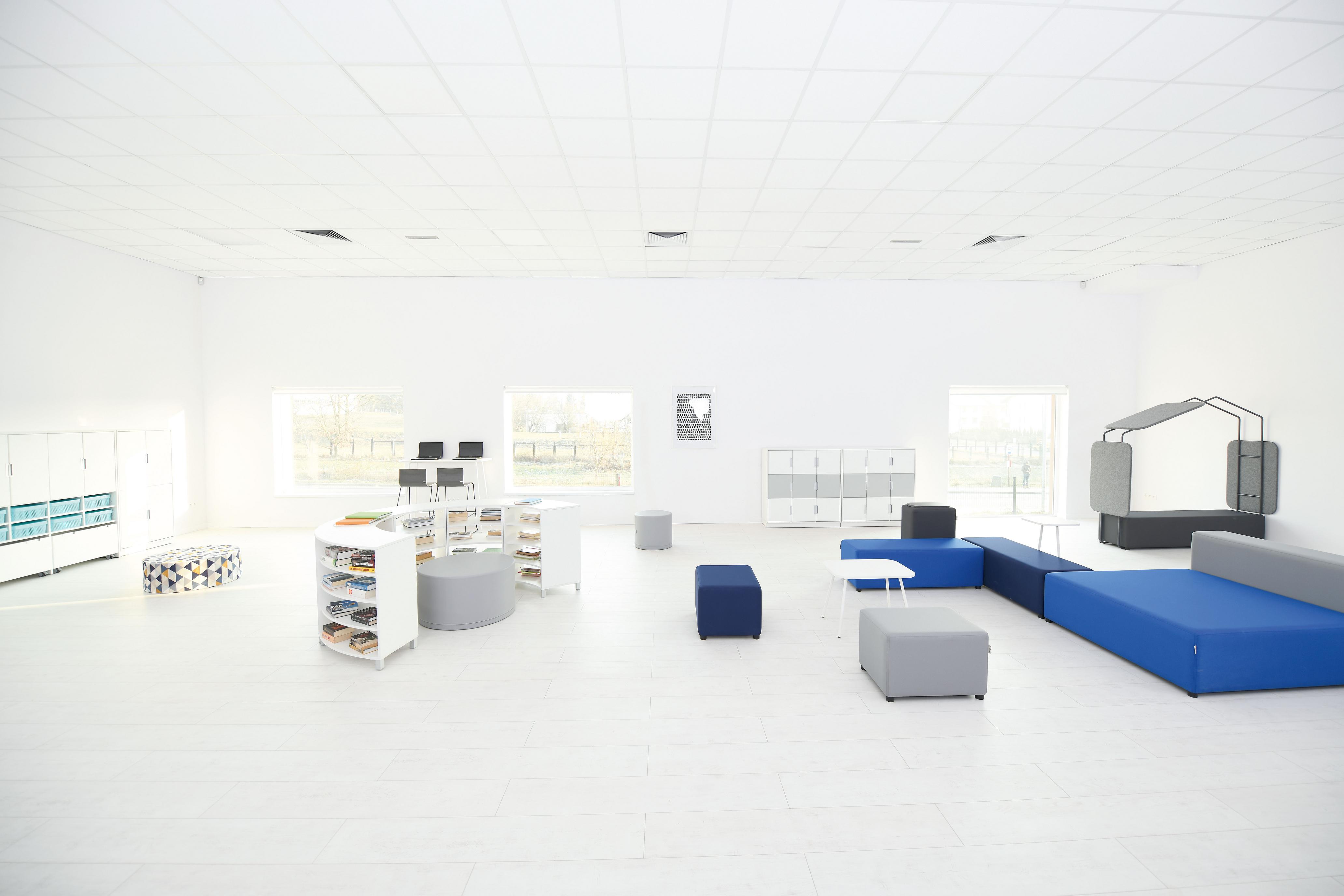 Modulare Sitzlandschaften aus blauen Loungemöbeln in Schulumgebung.