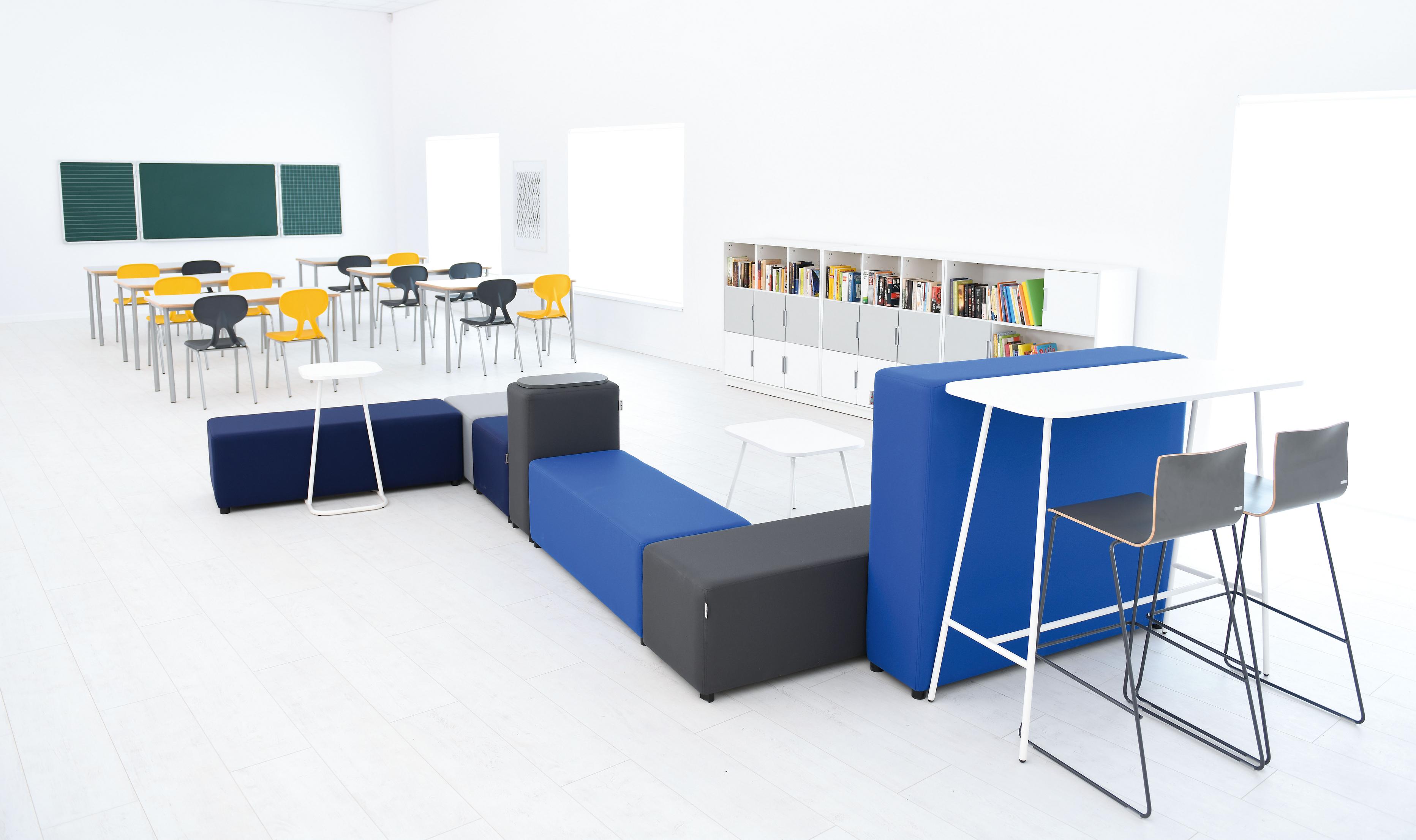 Konferenzraum mit Hochtisch, bunten Stühlen und Regalen.