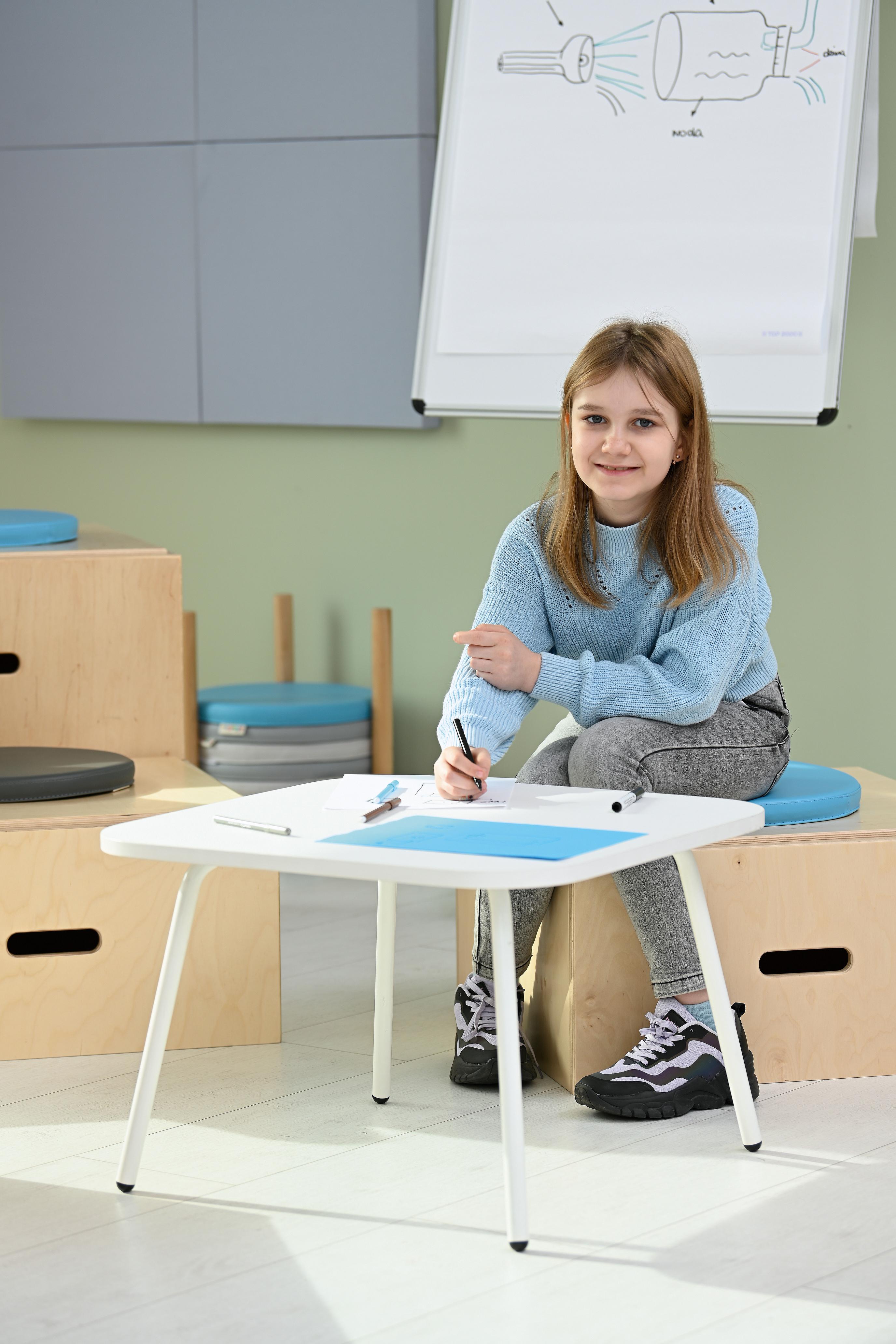 Mädchen beim Schreiben am Beistelltisch mit 4 Beinen.