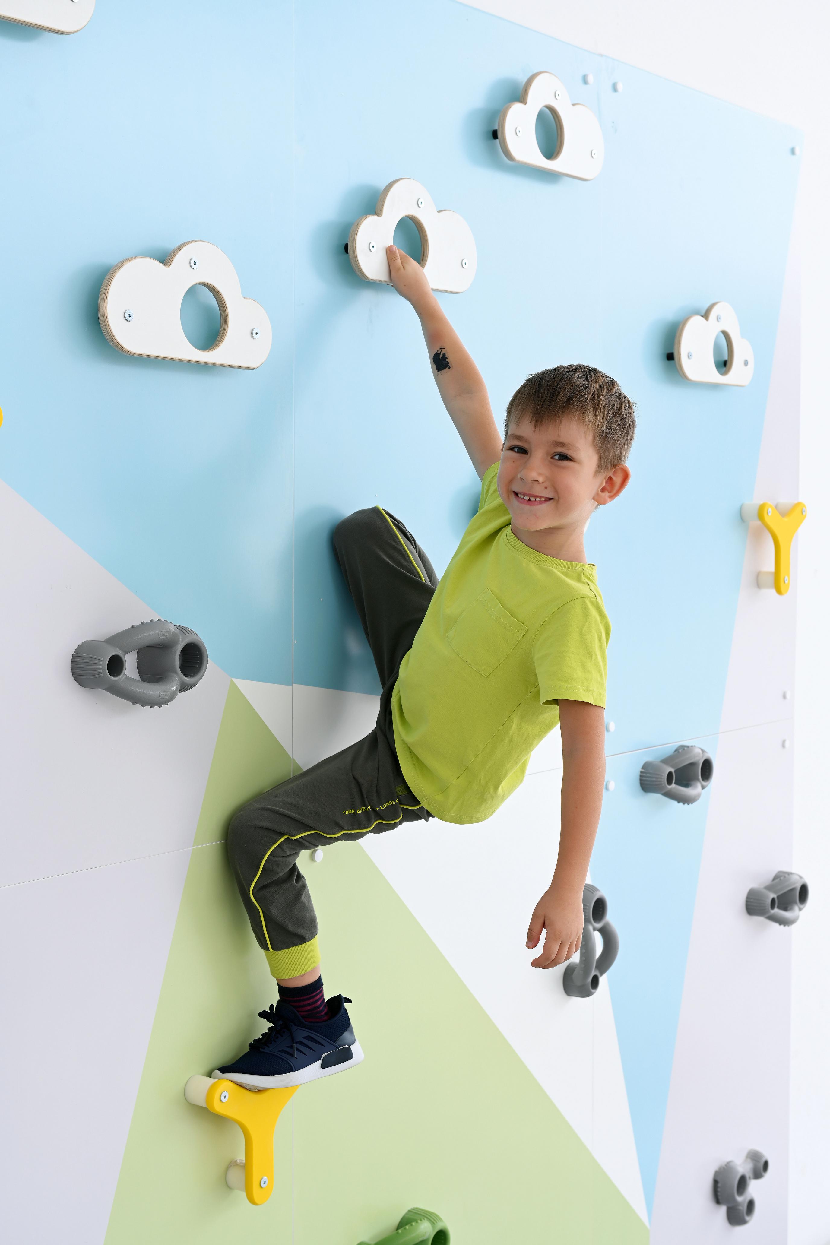 Kind klettert fröhlich an bunter Kletterwand.