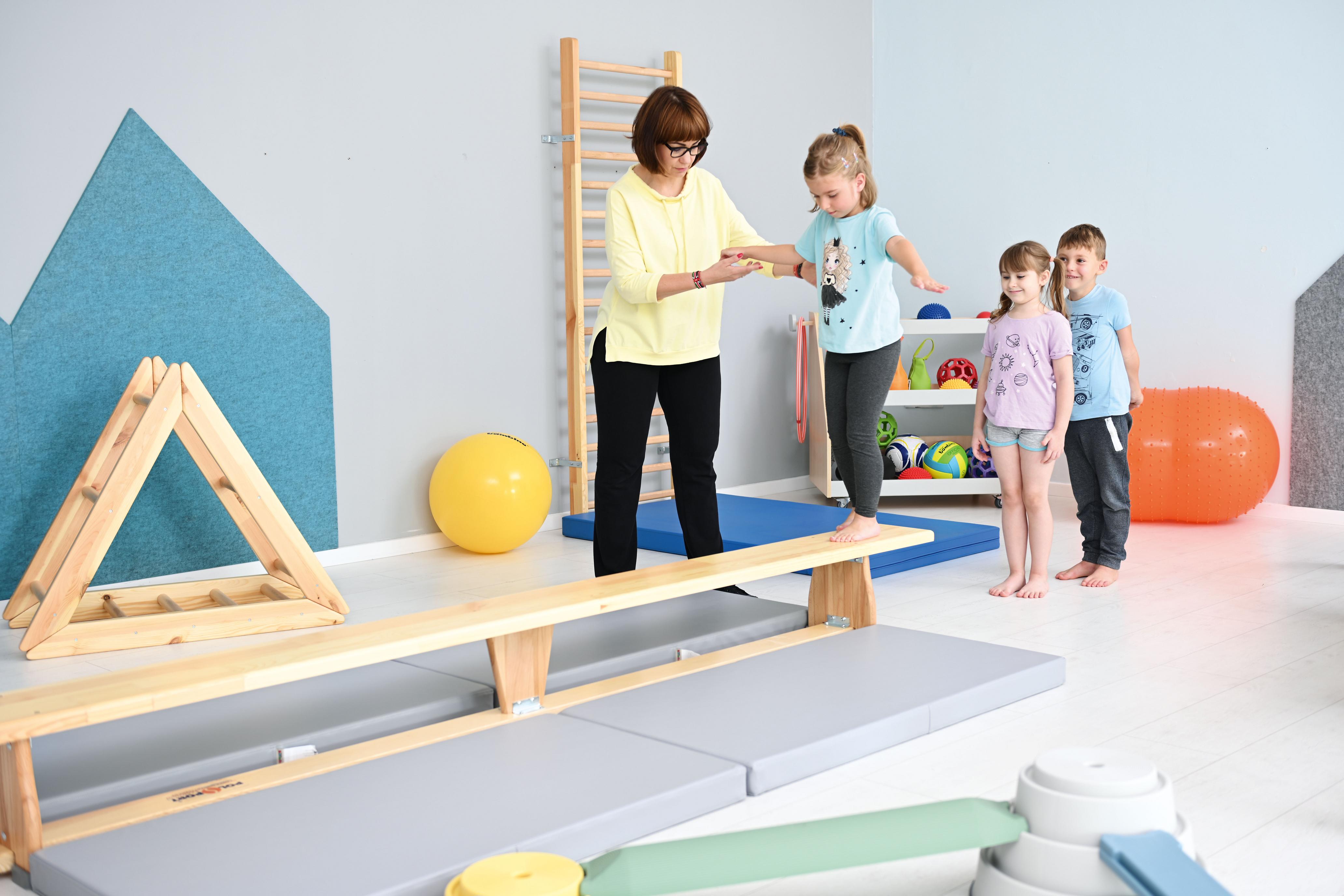 Kinder balancieren auf Turnbank 3 m im Gruppenraum.