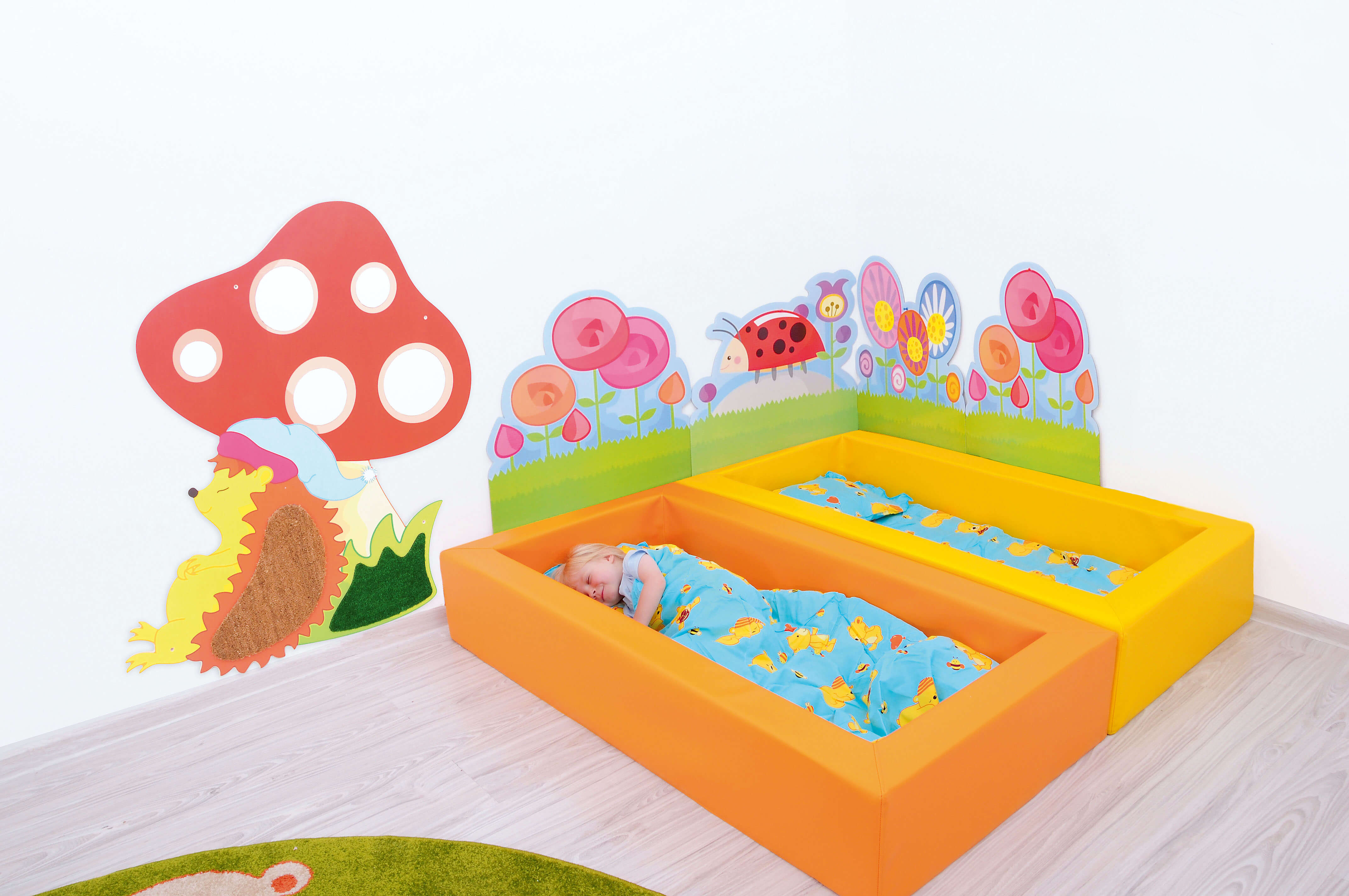 Ruheraum Krippenbett aus Schaumstoff gelb mit Bettwäsche und Kind