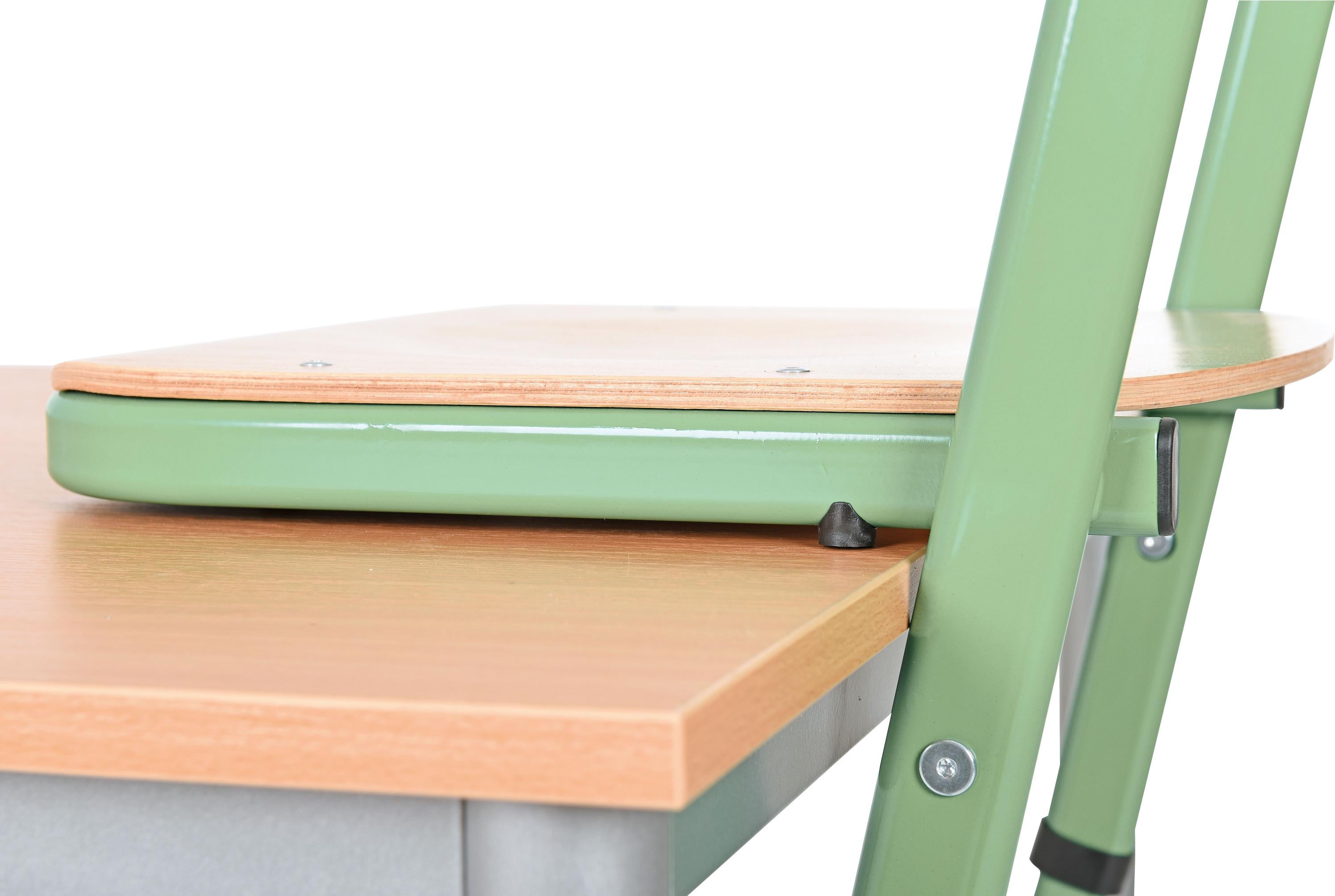 Schüler-Kufenstuhl in grün neben Tischkante positioniert.