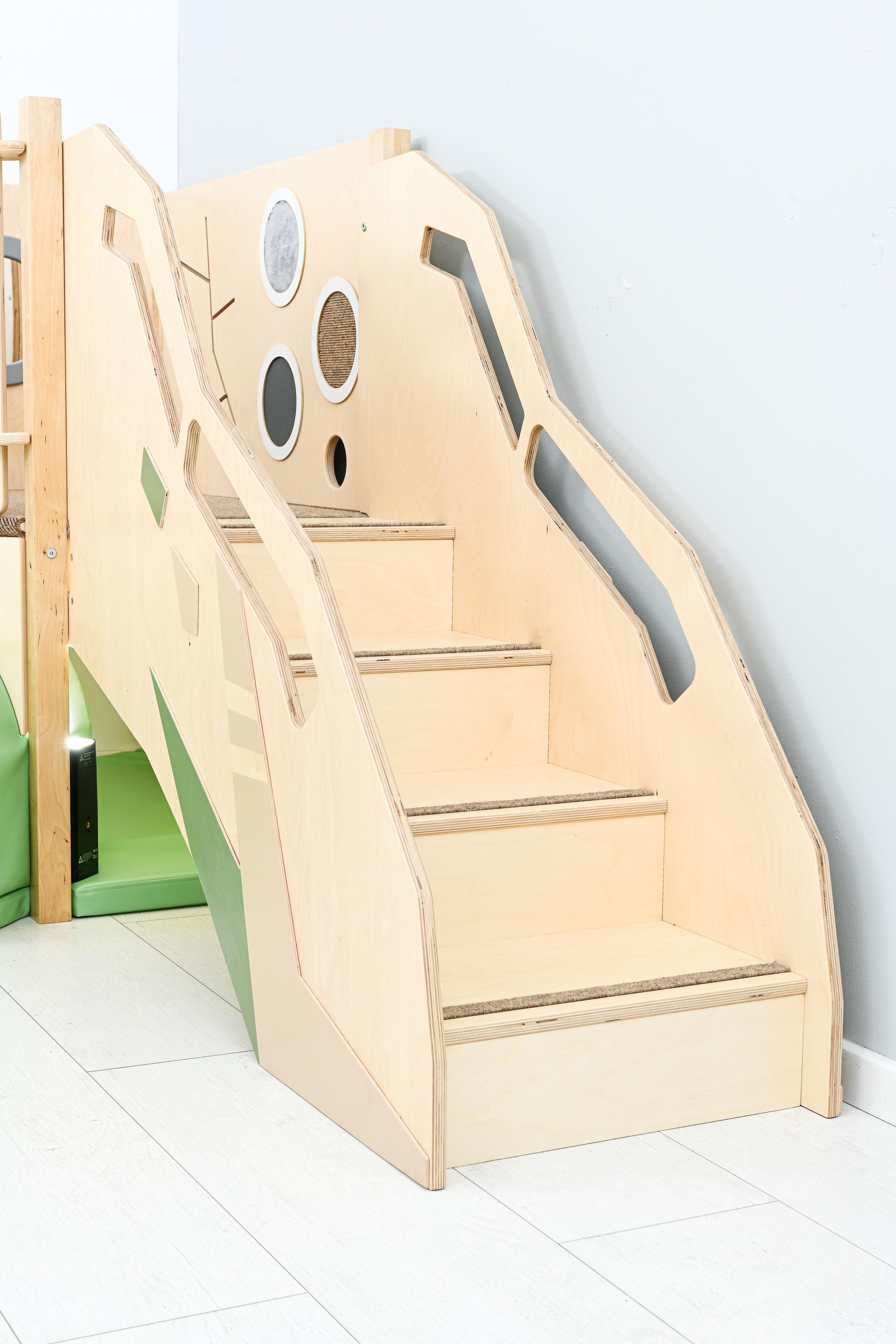 Sensorische Spielecke: Hochebene mit Treppe, naturfarbenes Holz.