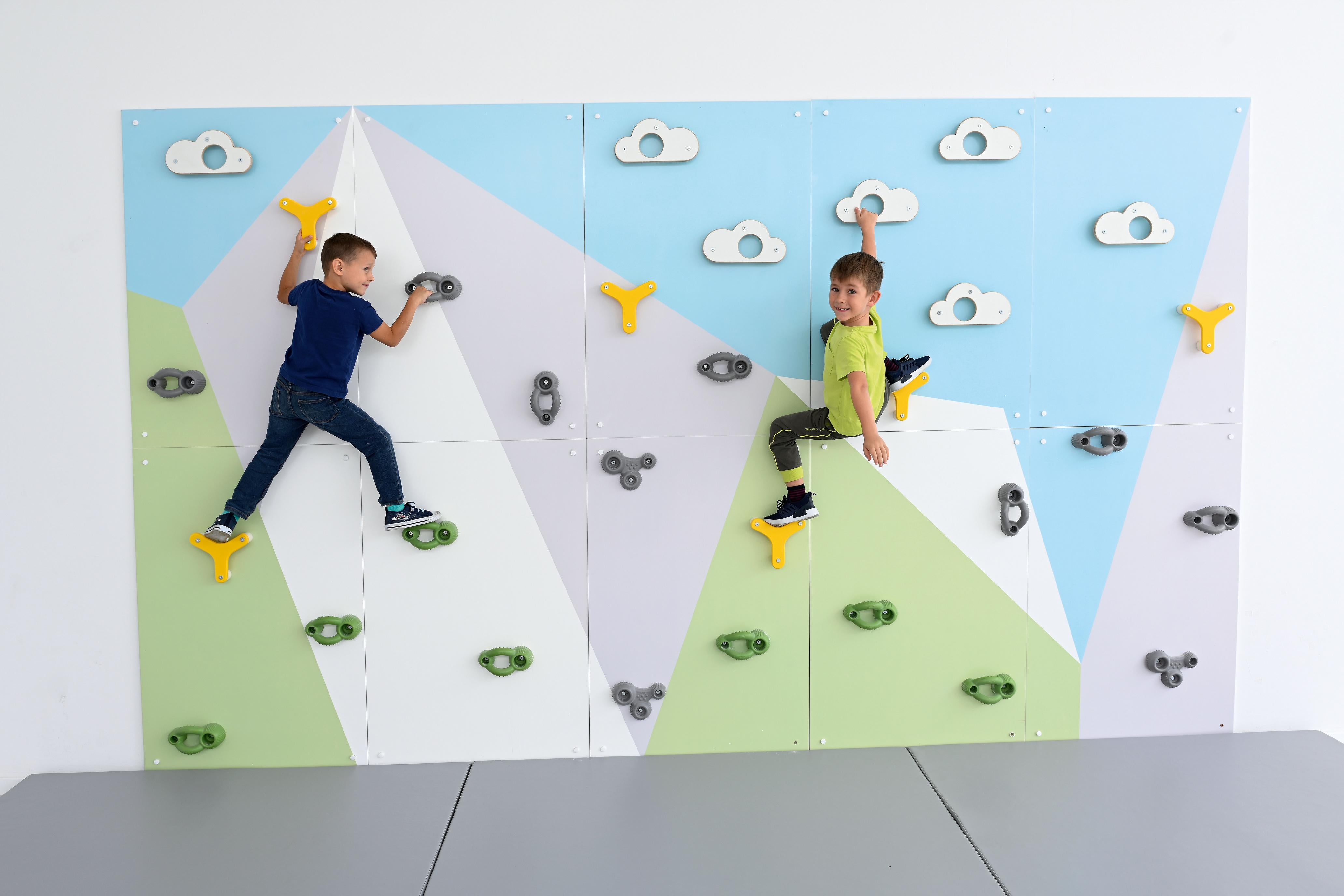 Zwei Kinder klettern auf bunter Kletterwand in Sporthalle.