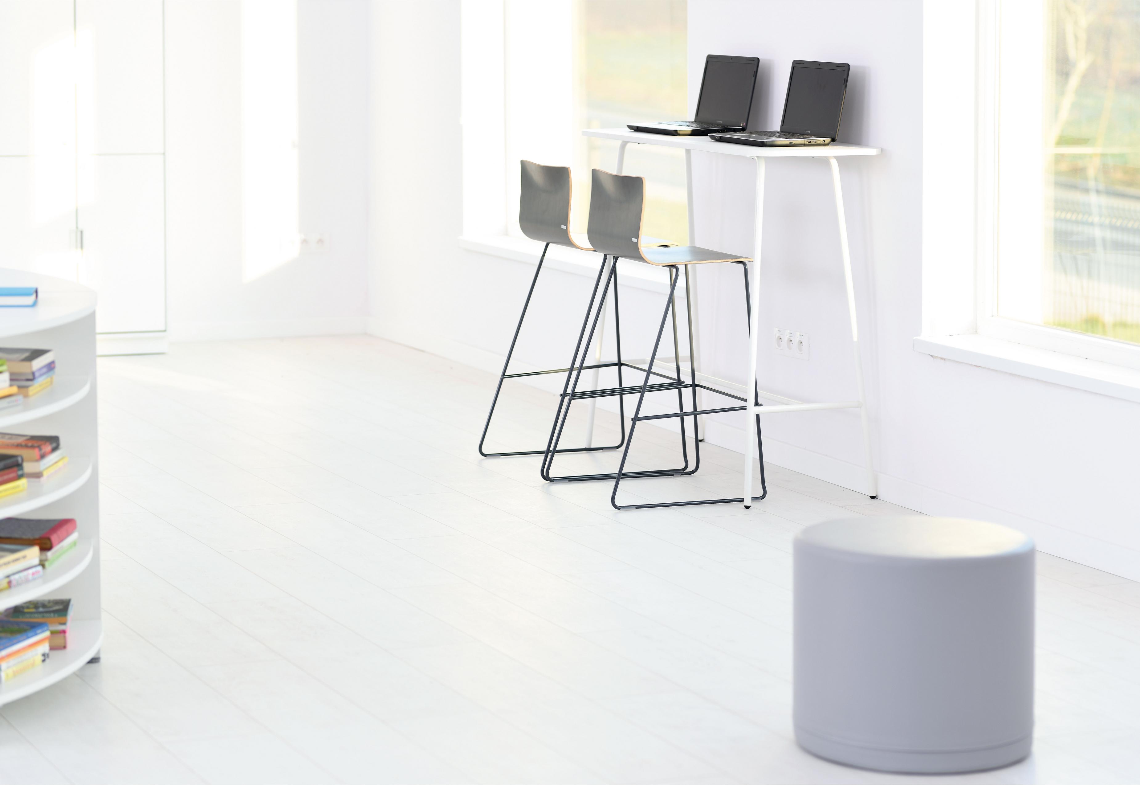 Zwei Barhocker vor weißen Tischen im Lernraum.