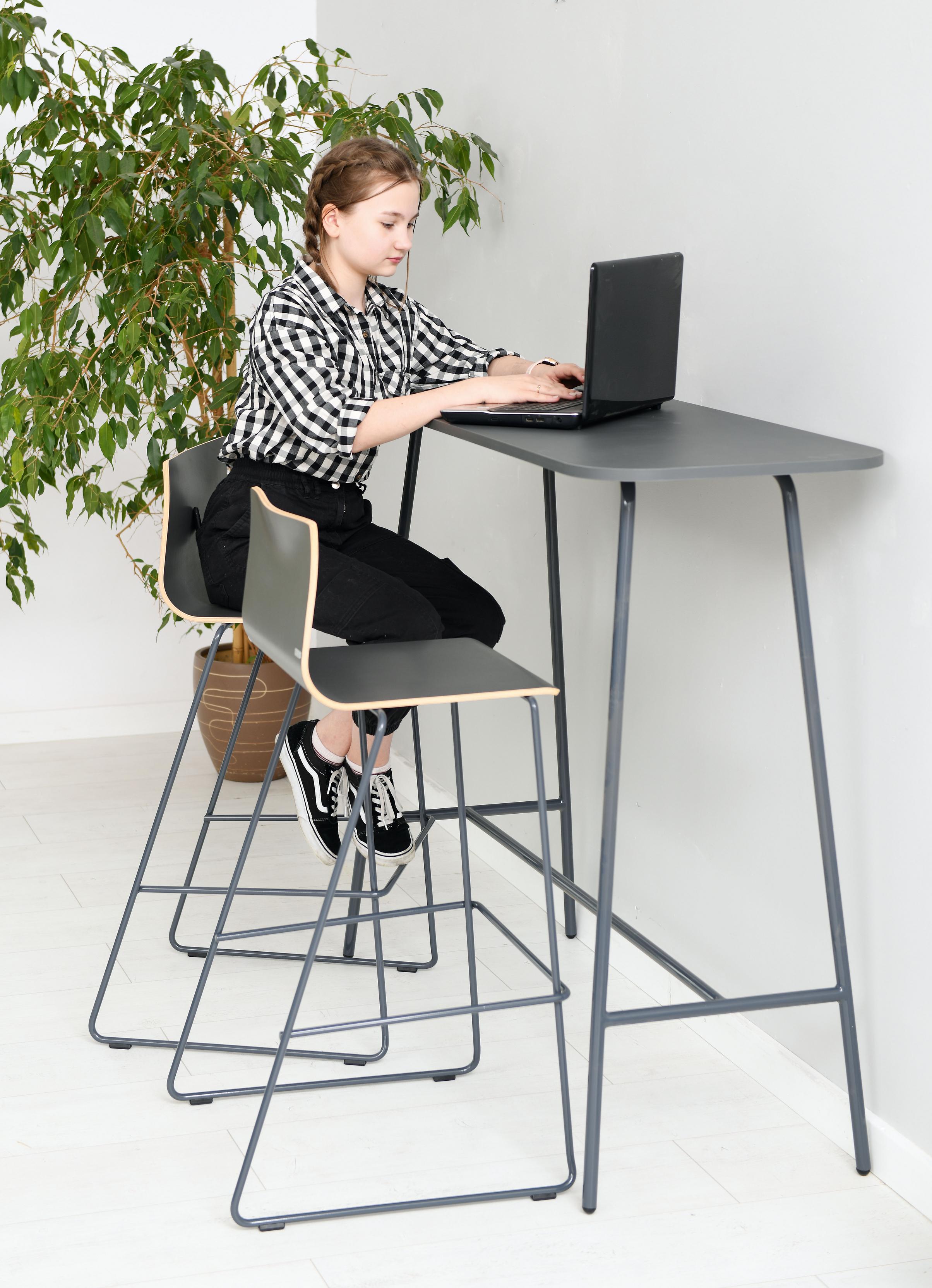 Person nutzt Laptop auf Barhocker im modernen Raum.