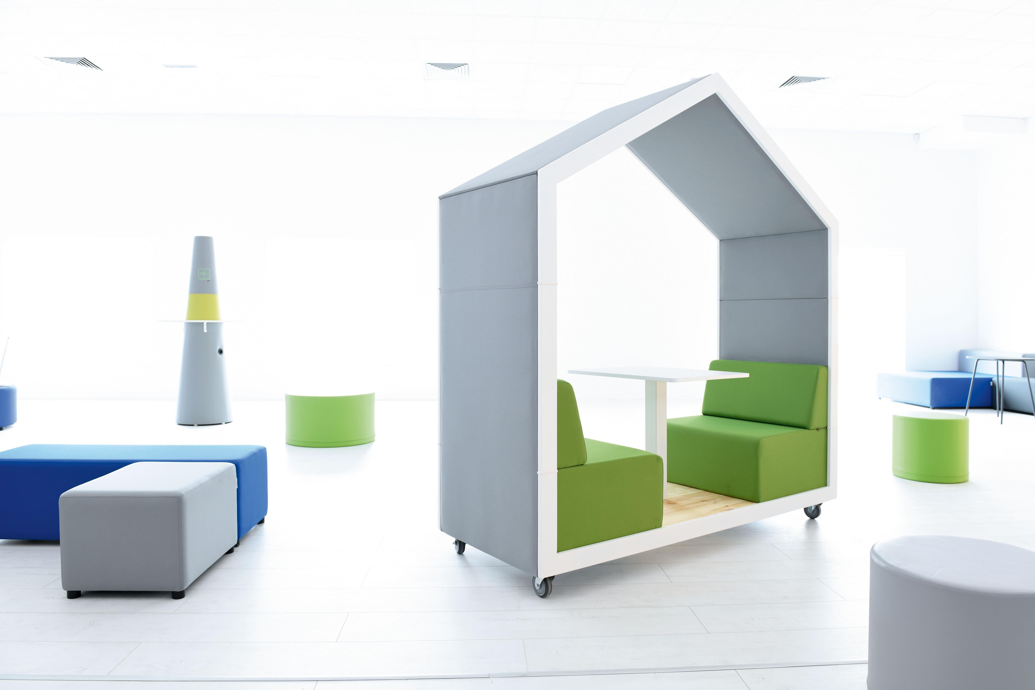Meeting box mit Tisch und grünen Sitzpolstern.