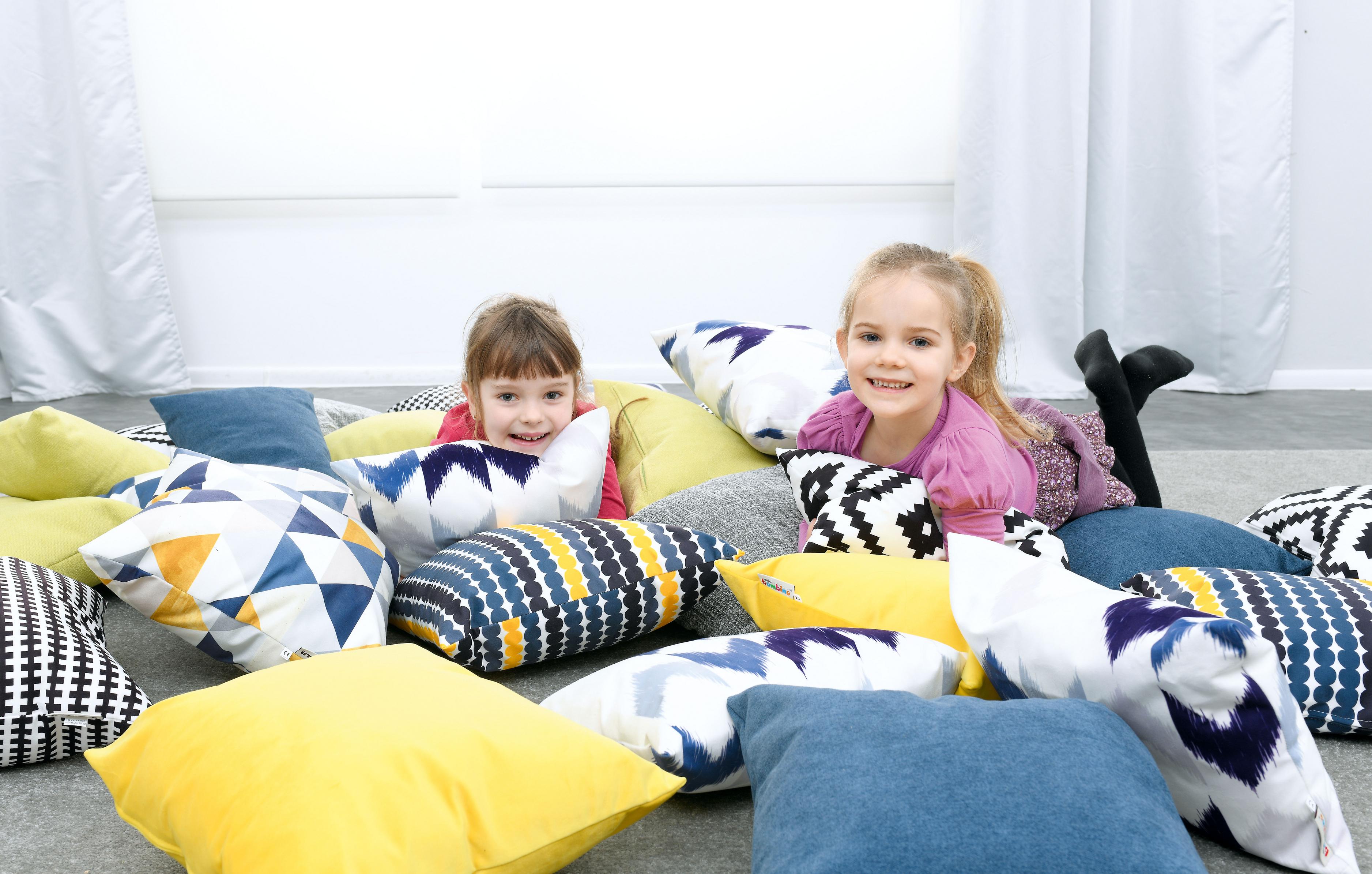 Kinder spielen fröhlich auf bunten Sitzlandschaftskissen.